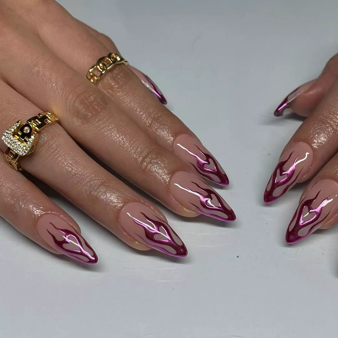 Person showing off their almond-shaped metallic nails with pink chrome flame hearts on the tip