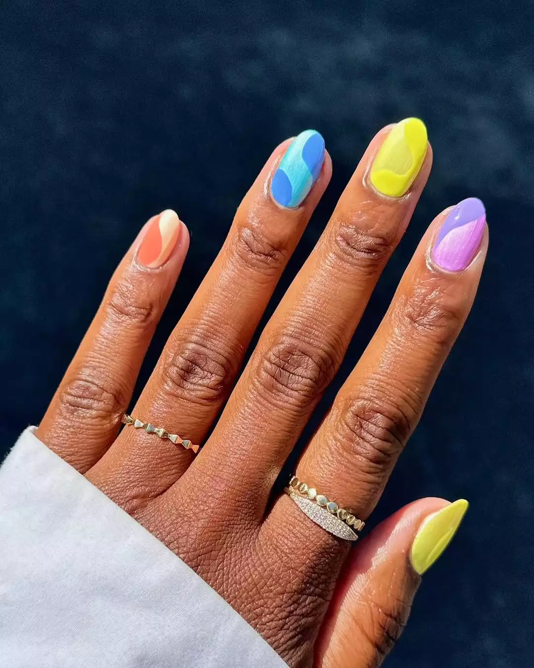 Person with round nails that are each painted in different colors with swirls