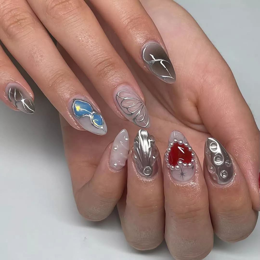 A closeup of hands with intricate artistic nail designs in metallic polishes