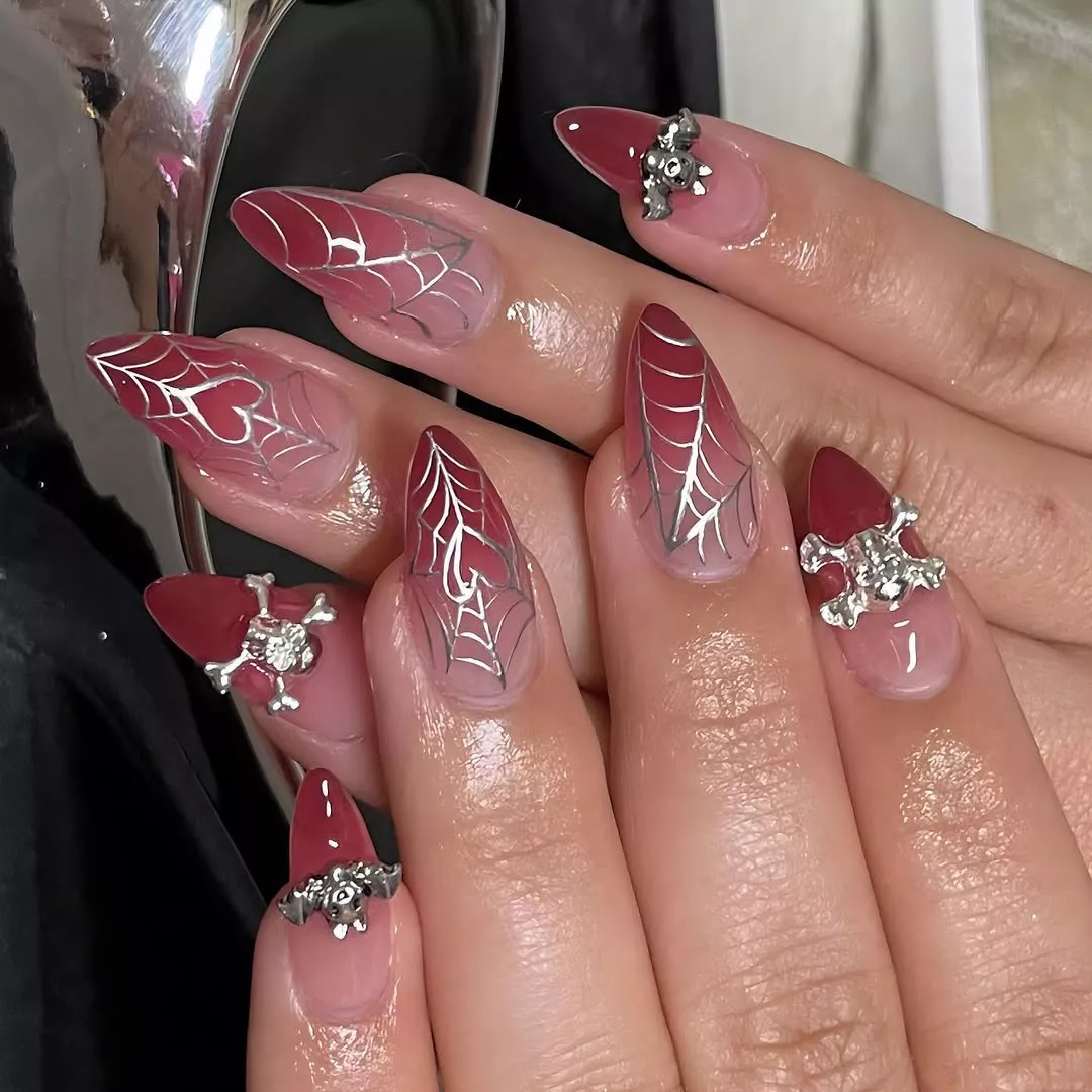 Hands with long pink ombre nails featuring spiderweb and jewel designs