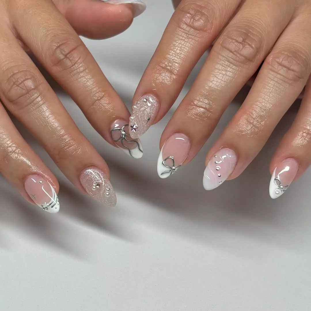 Person with short, round nails that have metallic accents like bows and dots