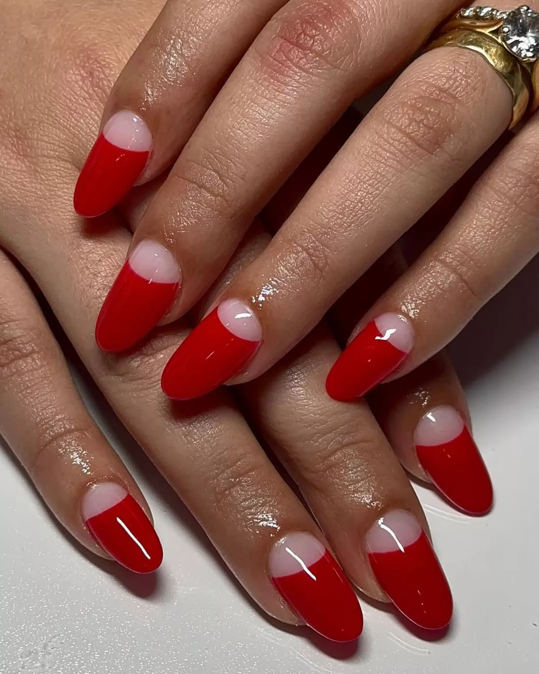 Person with long, rounded nails in a reverse French tip painted red
