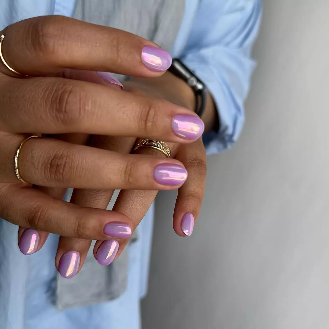 Person with round nails that are painted in an iridescent purple polish