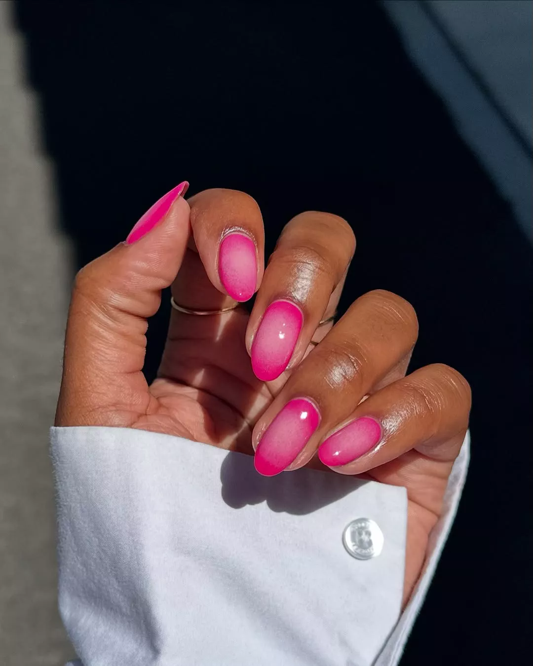 Person with medium-length round nails, which are hot pink on the edges and light pink in the middle