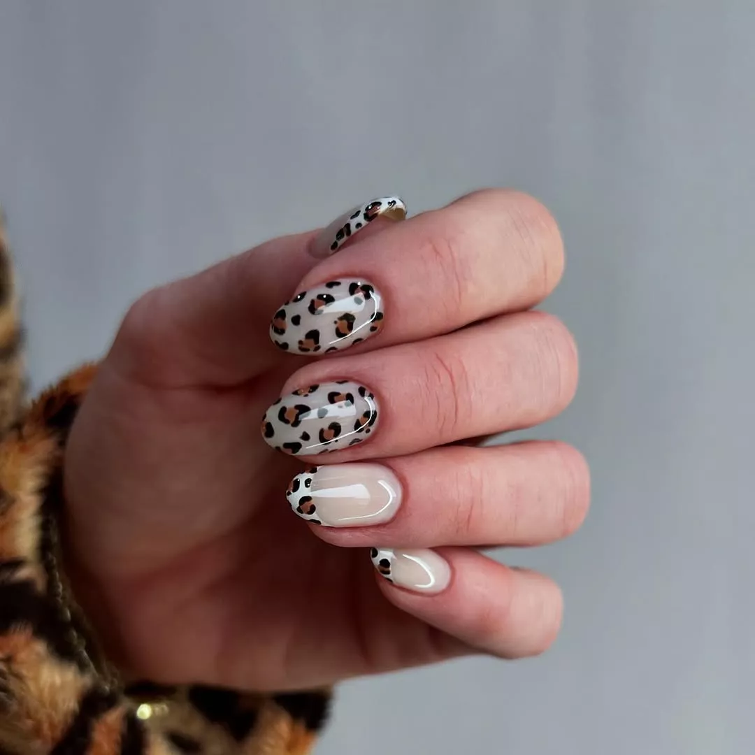 Person shows off their short, rounded nails which have leopard print on each finger