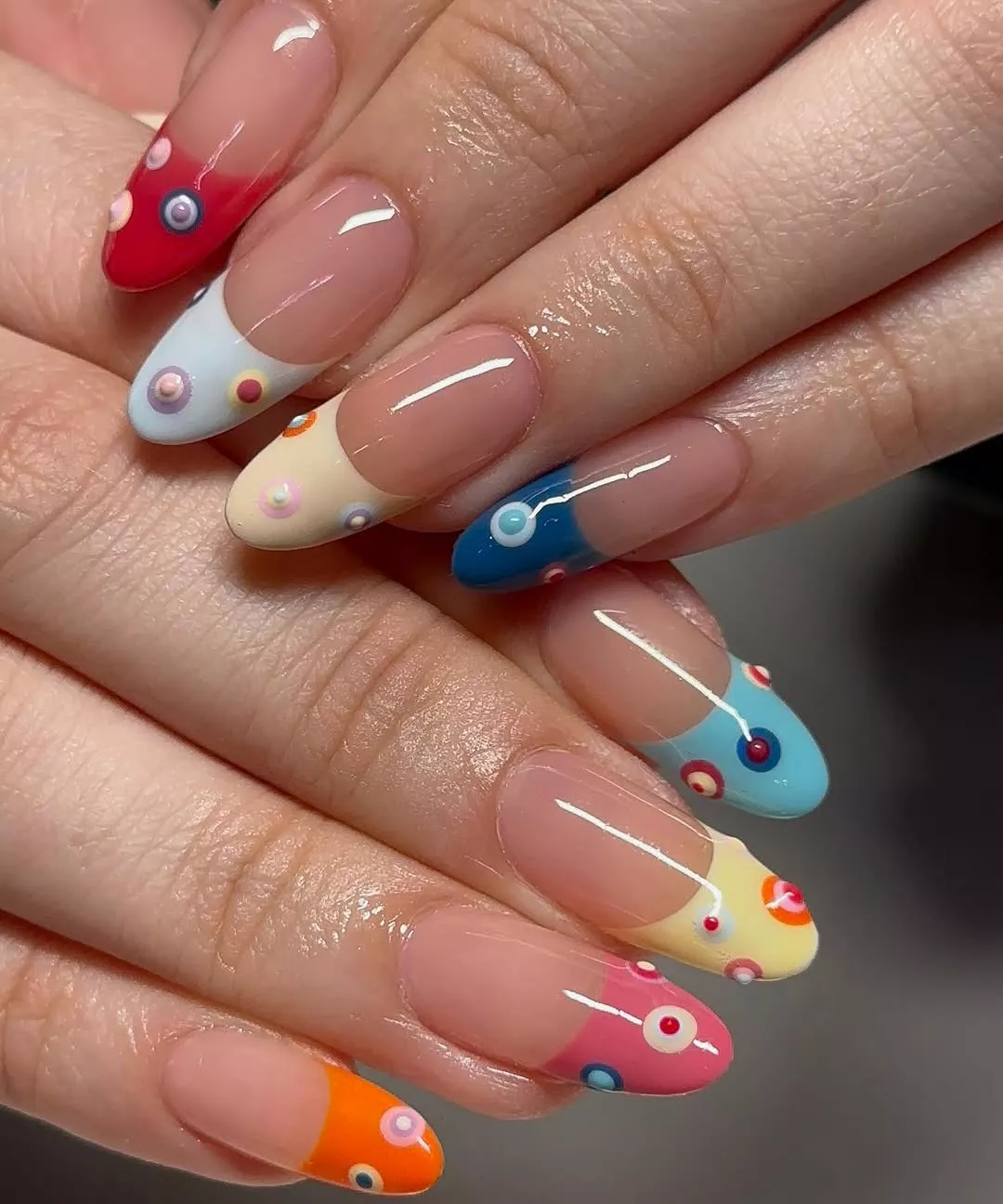 Person with round nails featuring French tips with 3D polka dots painted on each