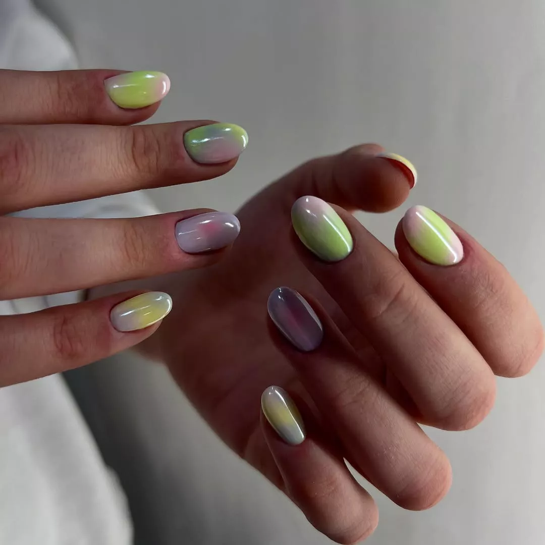 Person with round nails painted in glazed pastels of green, yellow, and pink