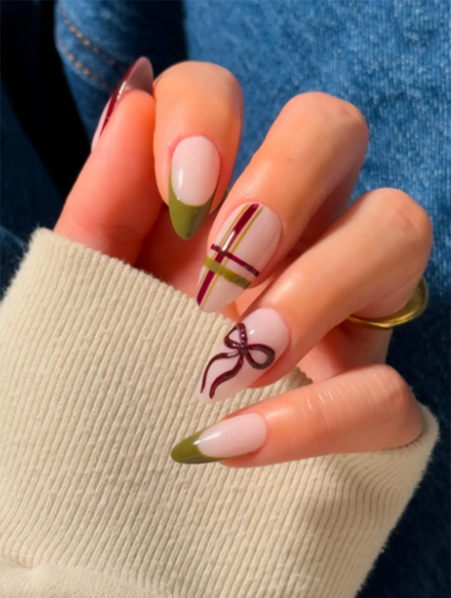 Hand with decorated nails featuring ribbon and stripe designs