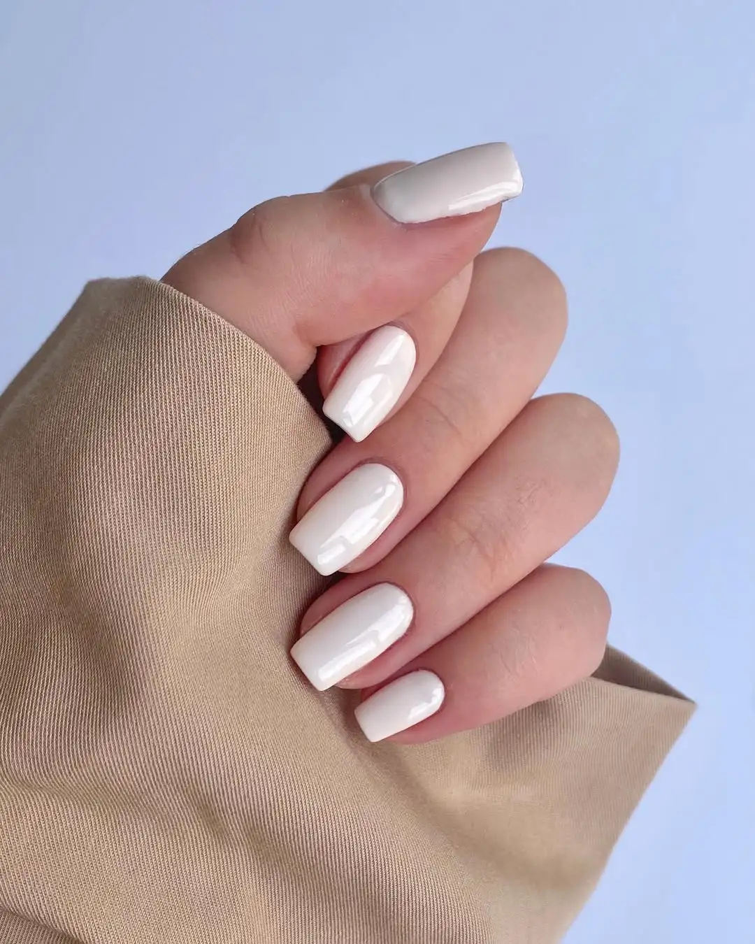 A person showing off a milky white manicure