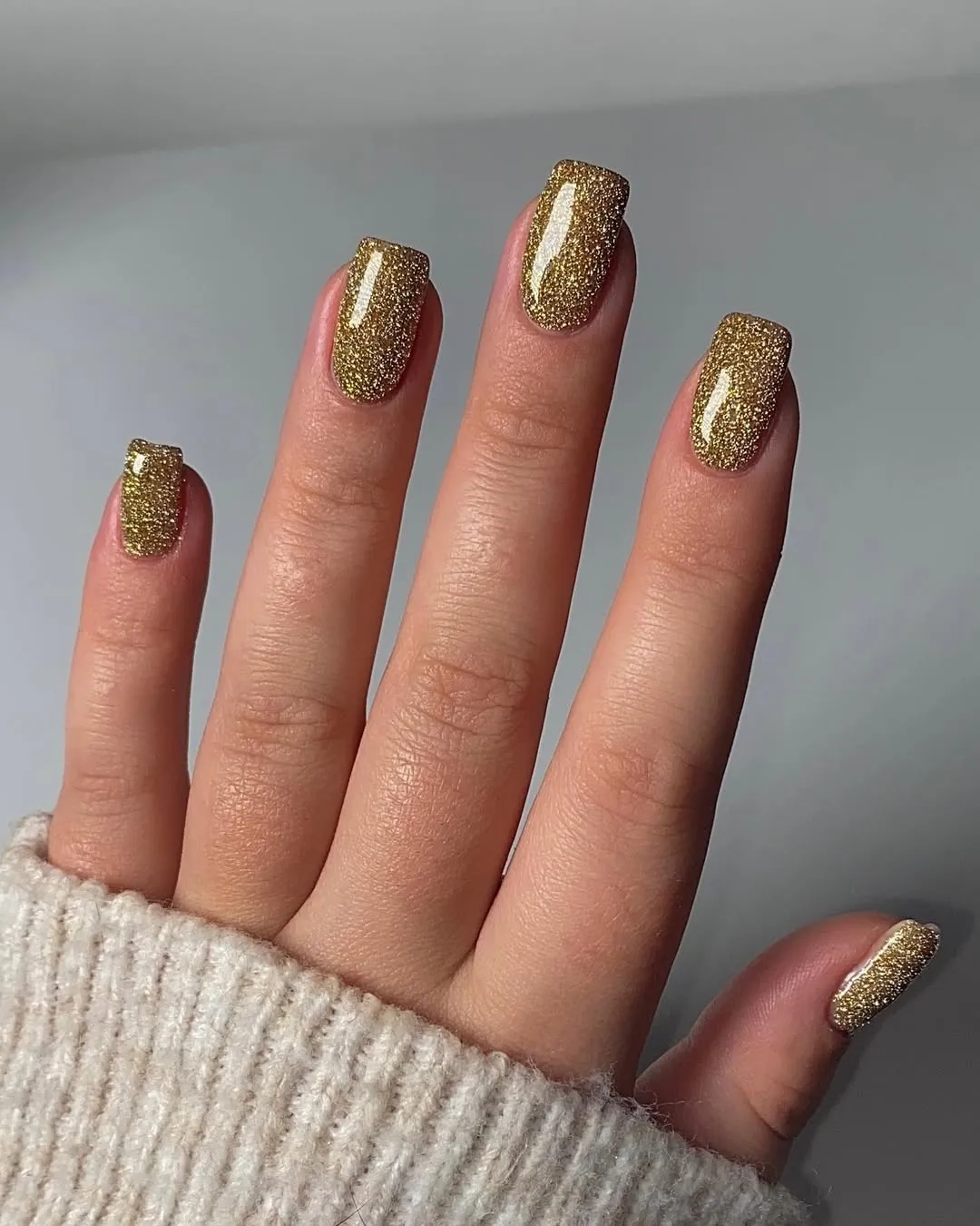 A person showing off a gold glitter manicure