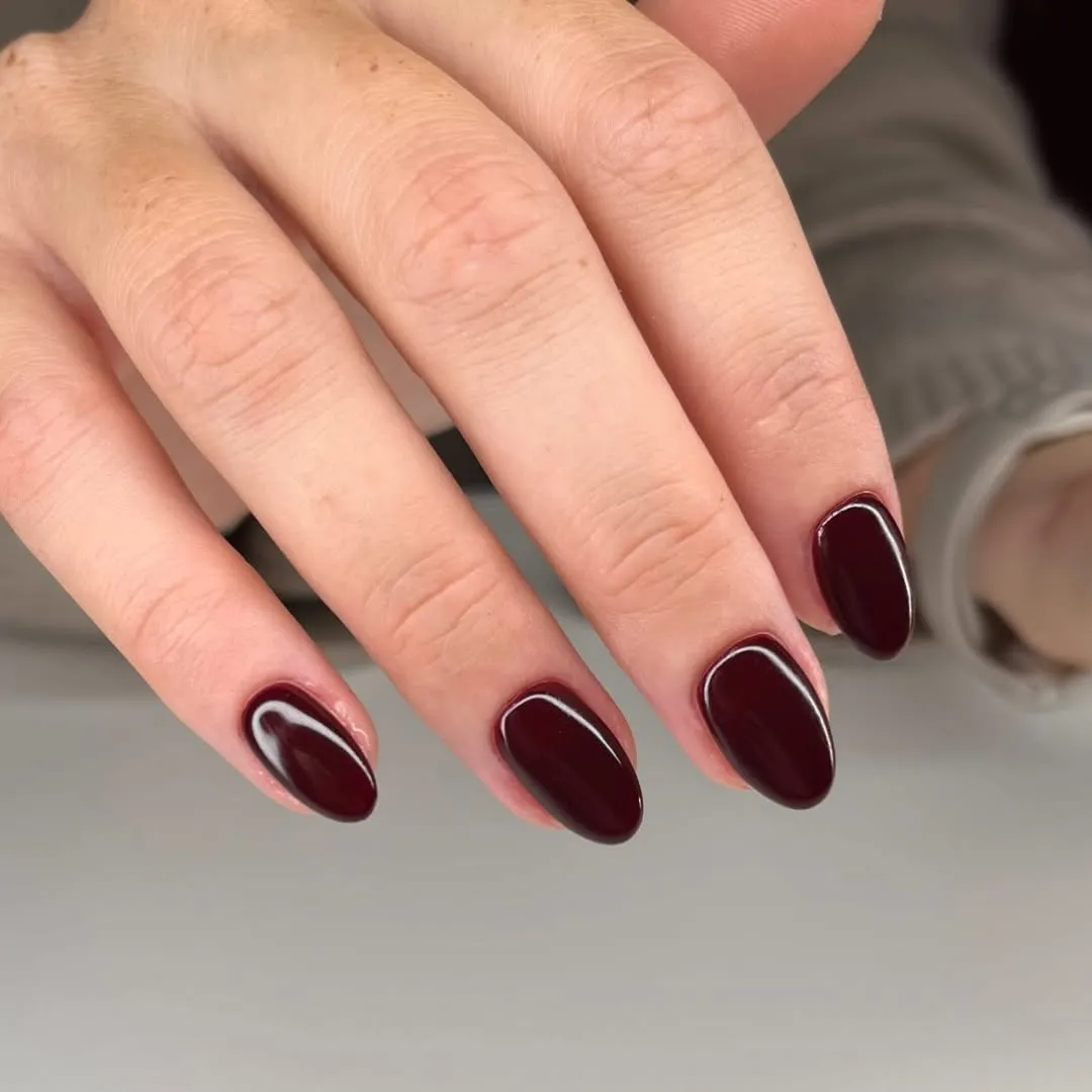 A person showing off a moody red manicure