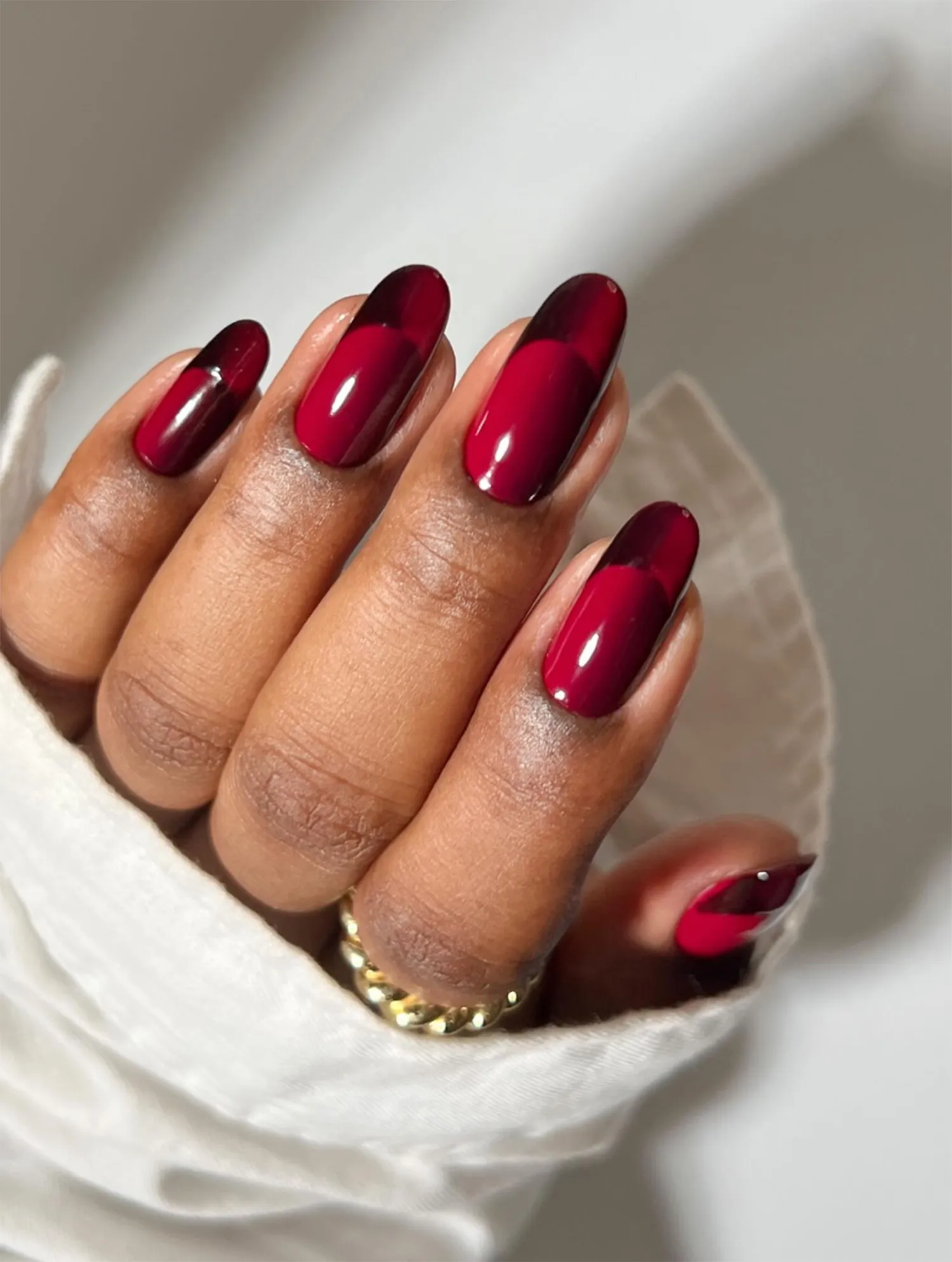 A hand with manicured nails painted in a red glossy finish