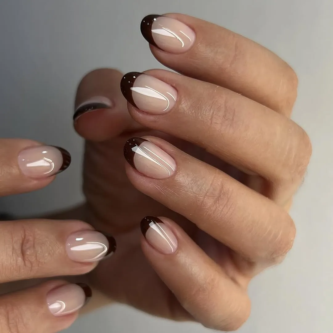 A person showing off a chocolate French manicure. 