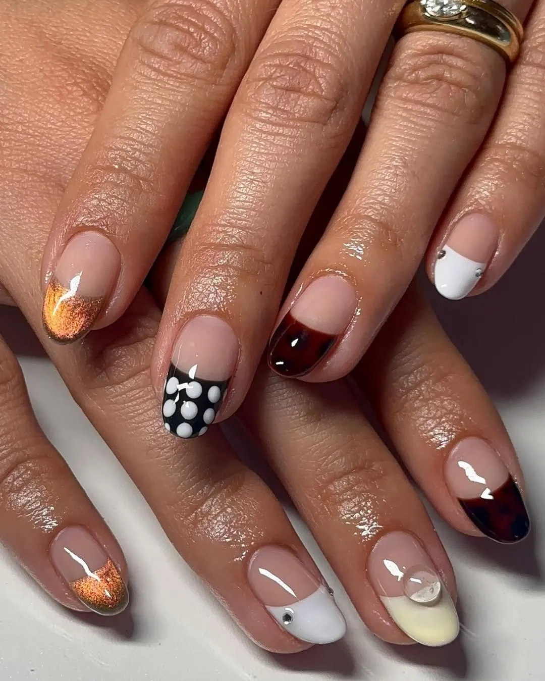 A person showing off a French manicure with metallic and tortoise tips