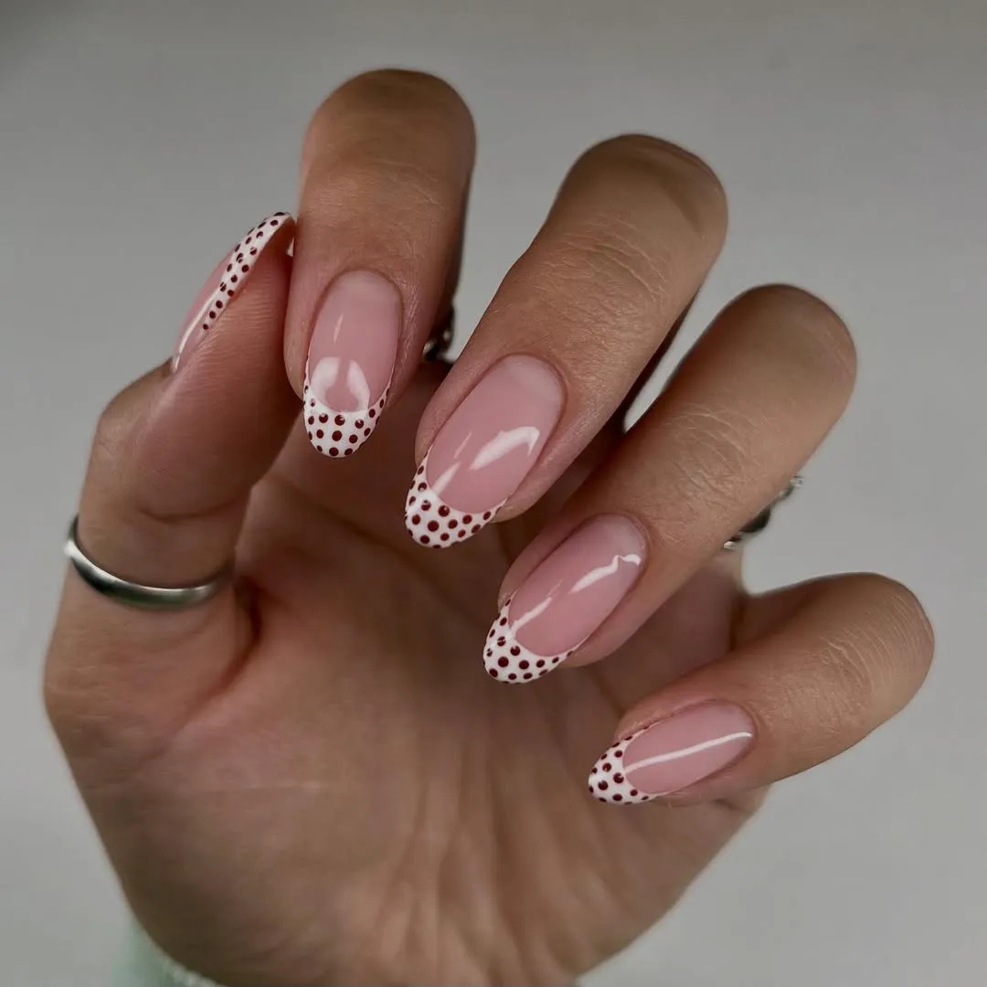 A person showing off a dotted French manicure