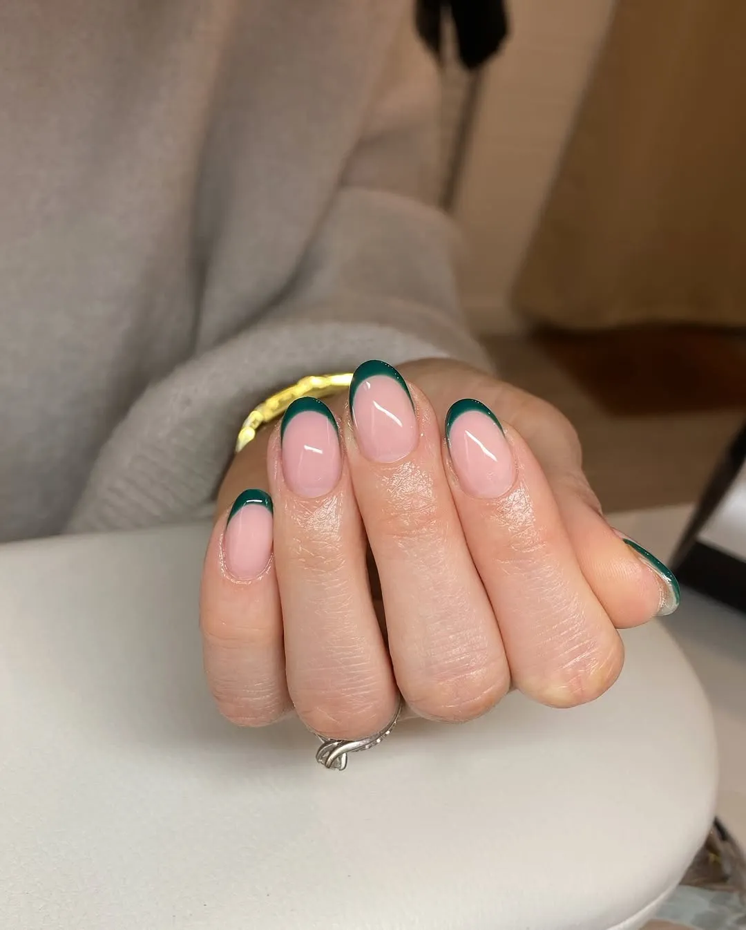 A person showing off a dark green French manicure