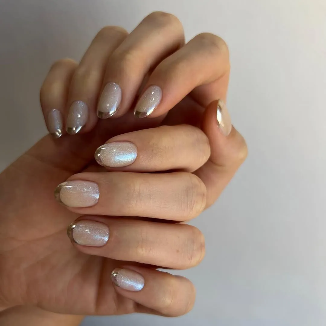 A person showing off a gold-tipped manicure