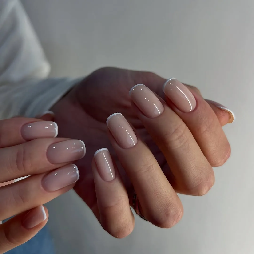 A person shows off a white micro French manicure