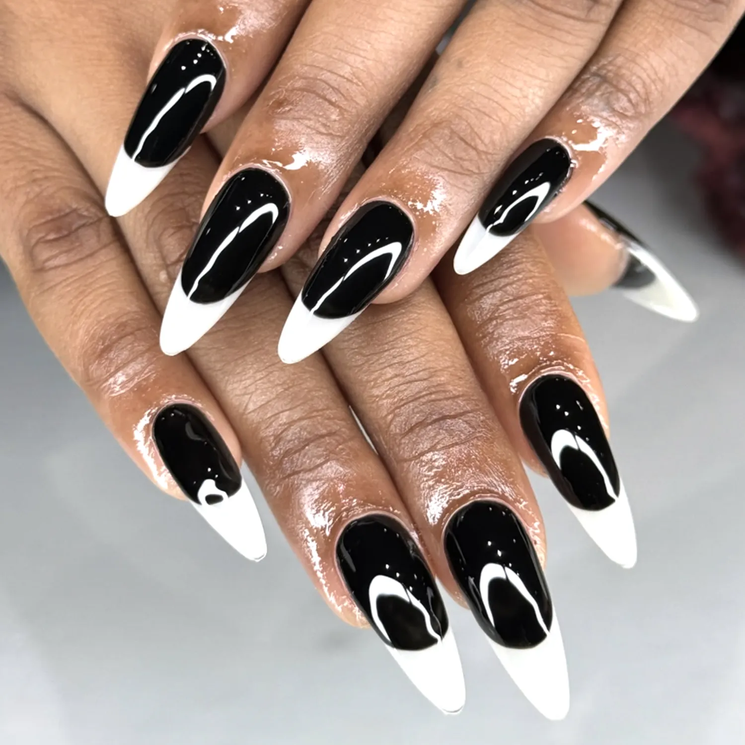 Closeup of hands featuring nail art with black designs and white tips
