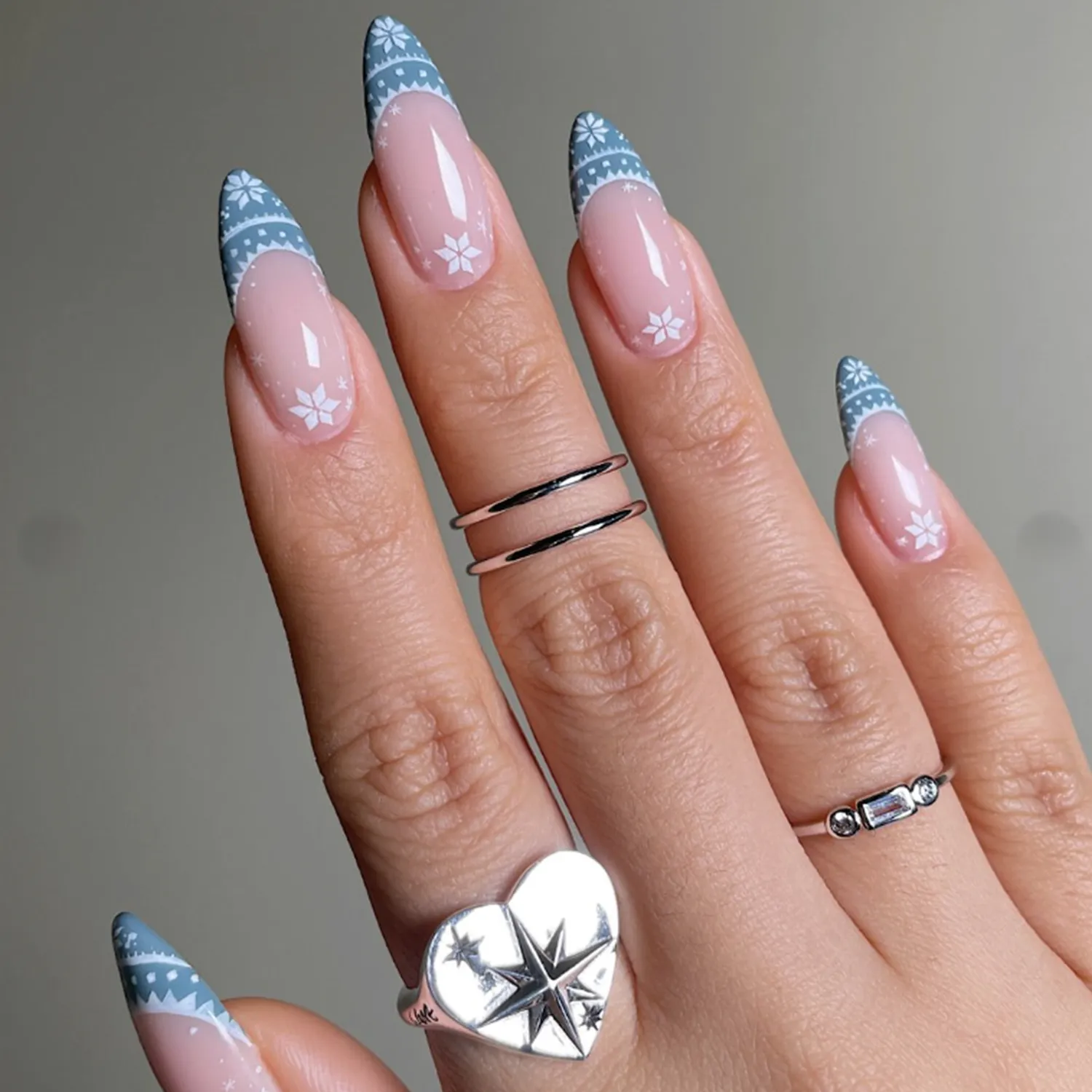 A hand showing winterthemed nail art with snowflake patterns on tapered nails