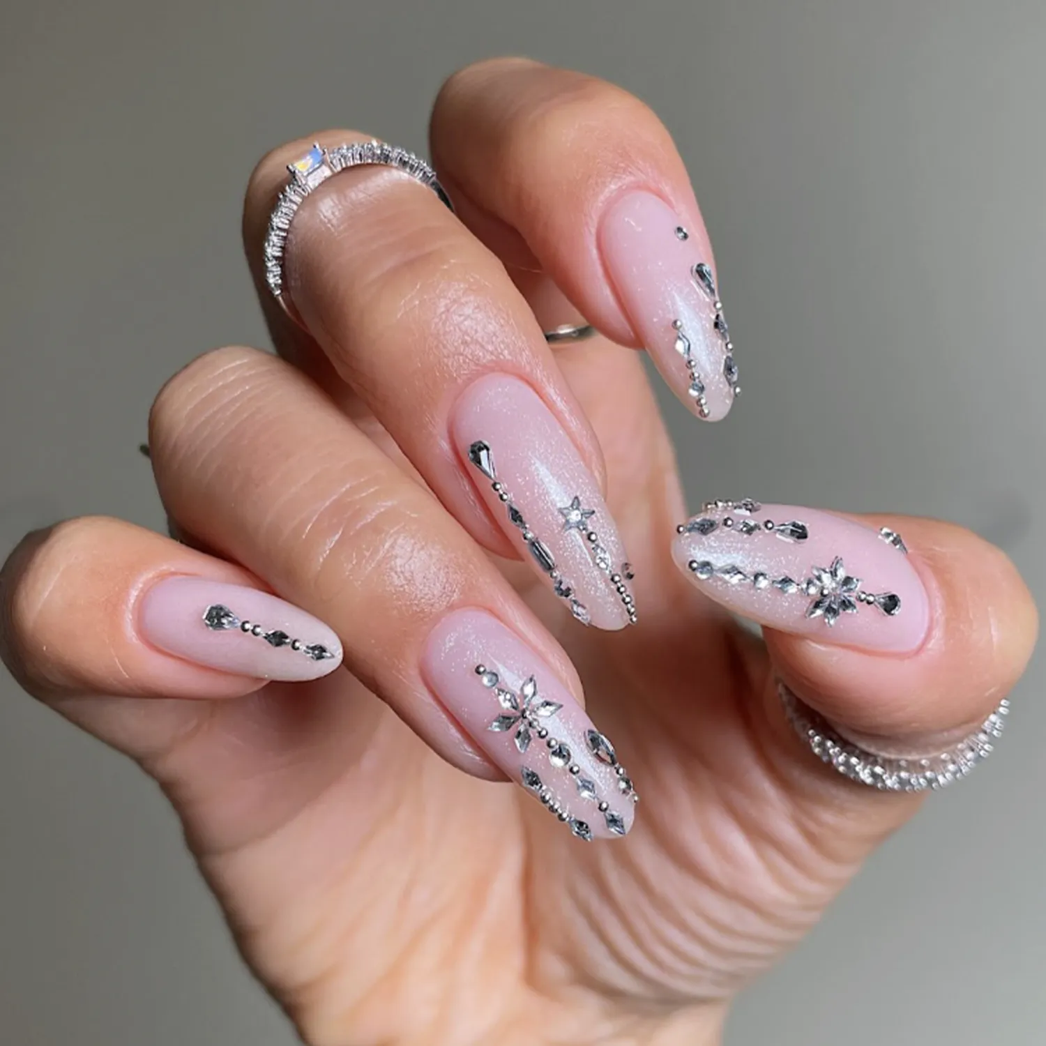 A hand with long nails featuring an intricate winterthemed design with sparkling accents and delicate patterns