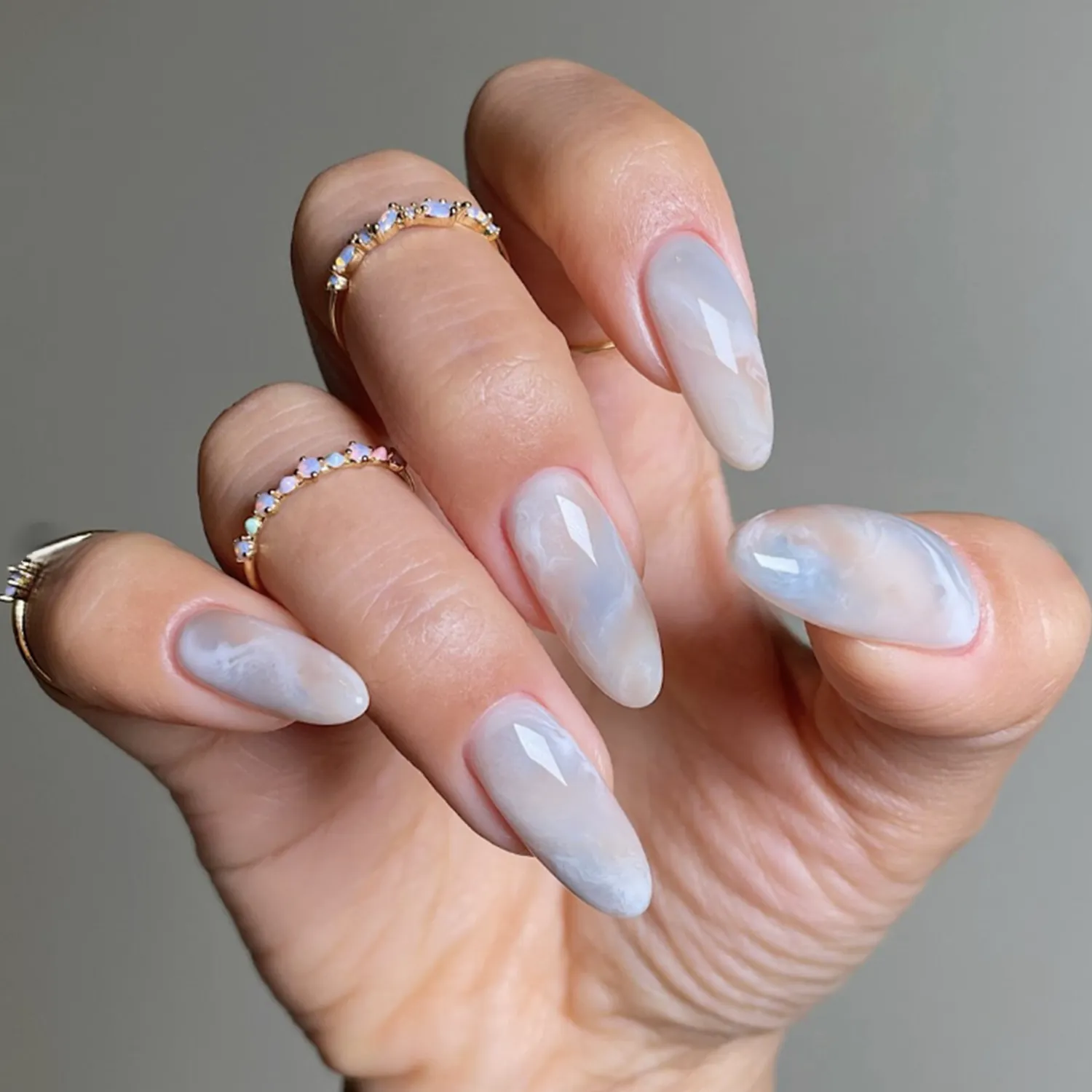 A closeup of a hand with long polished nails and several rings on the fingers
