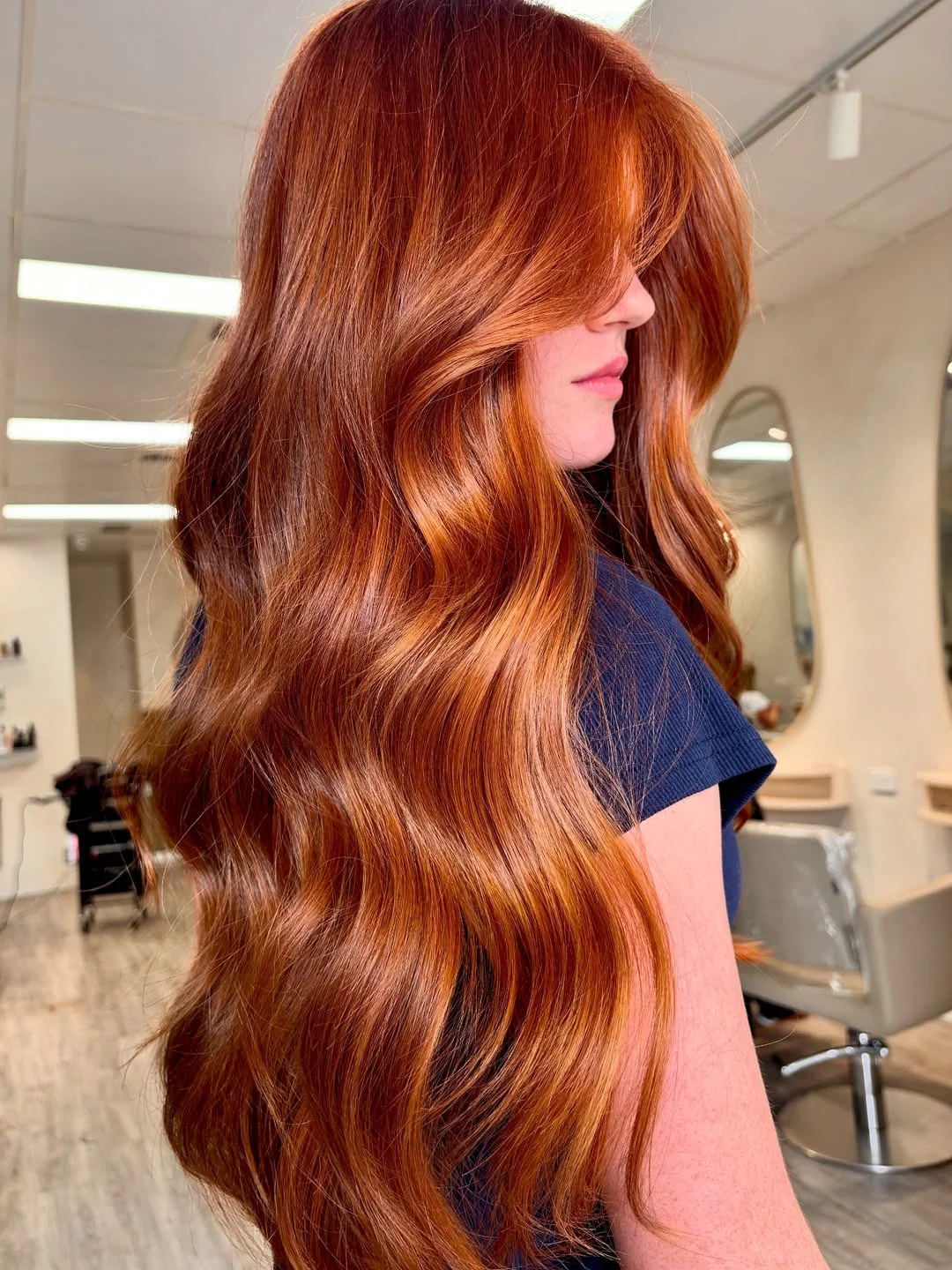 A woman with radiant copper hair styling a chic white halter neck top and high-waisted denim shorts, perfect for copper hair summer ideas 2026. She exudes casual elegance.
