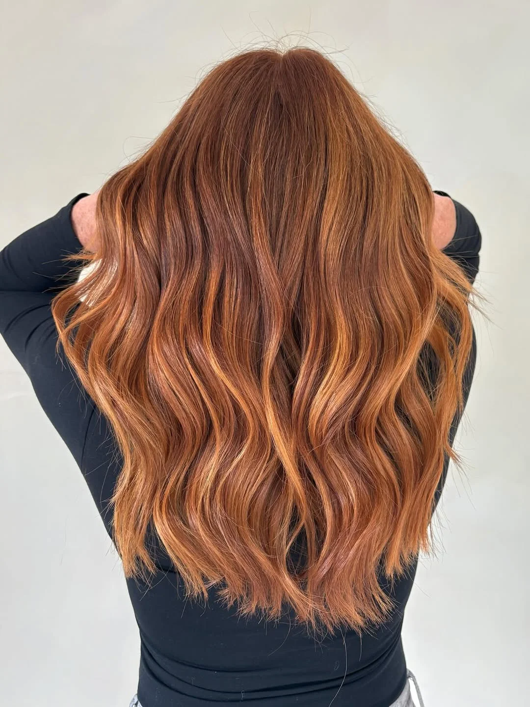 A woman with vibrant copper hair wearing a flowy white sundress, sunglasses, and a wide-brimmed straw hat, embodying perfect copper hair summer ideas 2026.