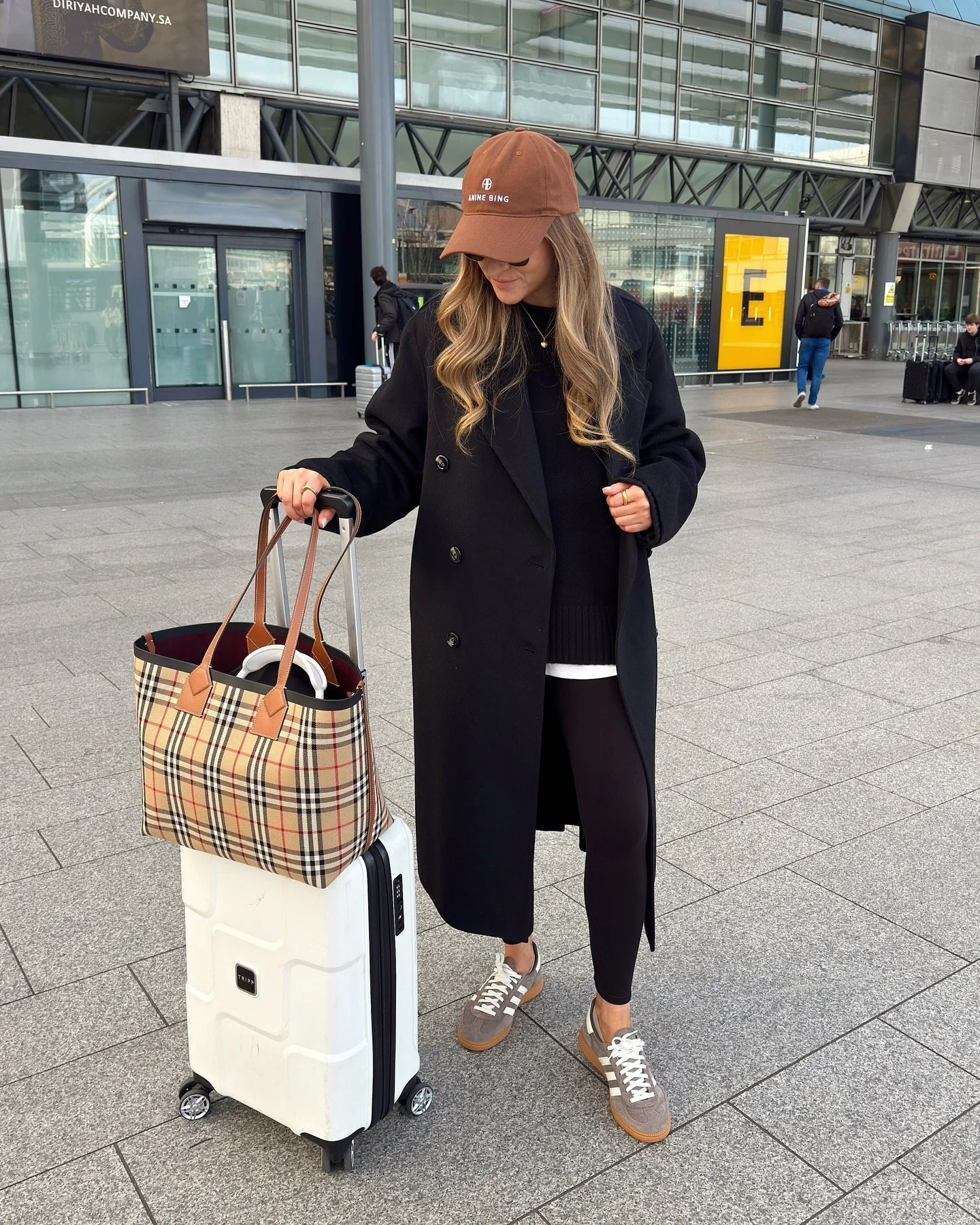 Chic Airport Look With Black Coat And Tartan Tote