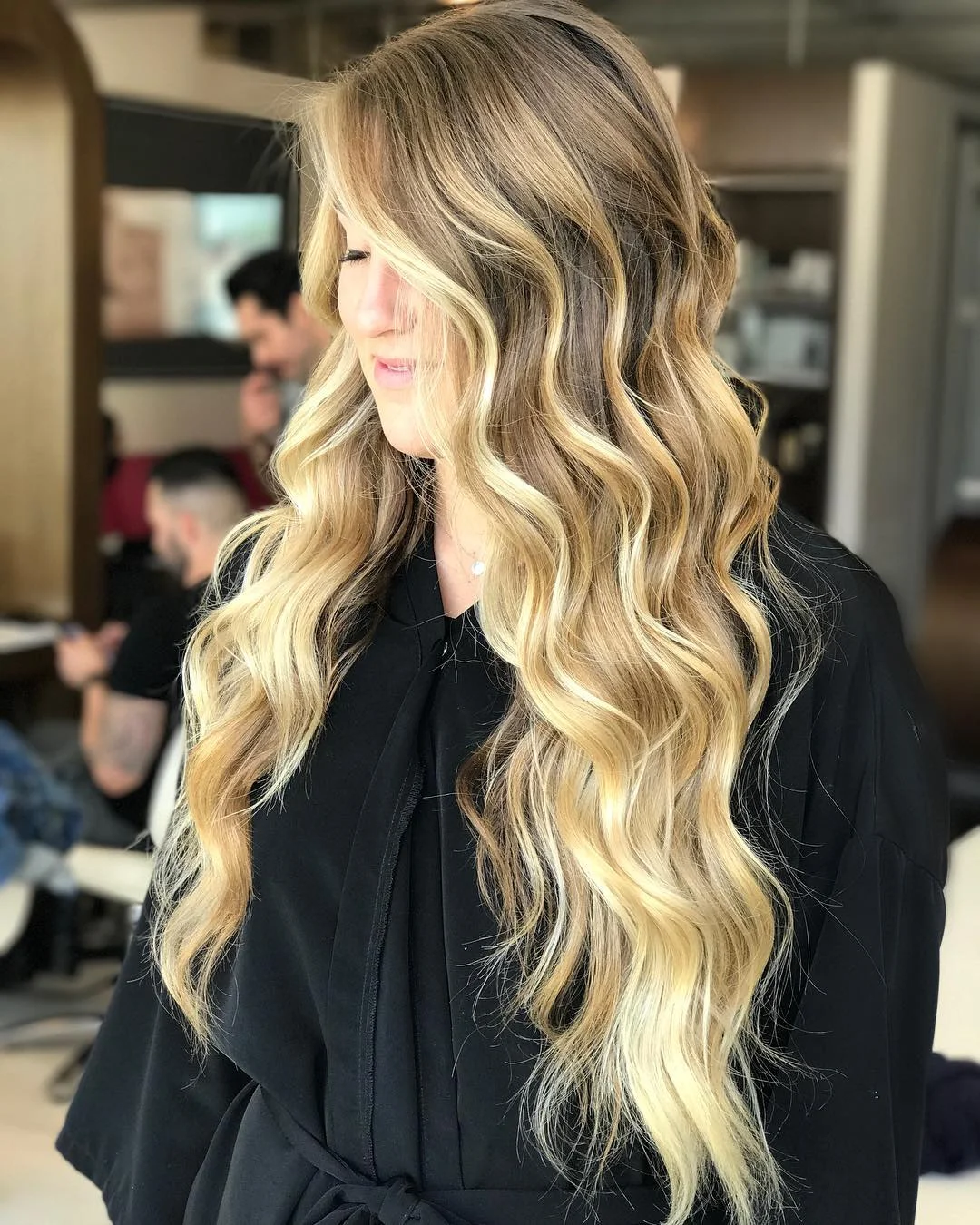 Woman with long flowing blonde hair styled in loose waves, enjoying a sunny summer day. Perfect long hair summer hairstyles 2026 inspiration for effortless chic.