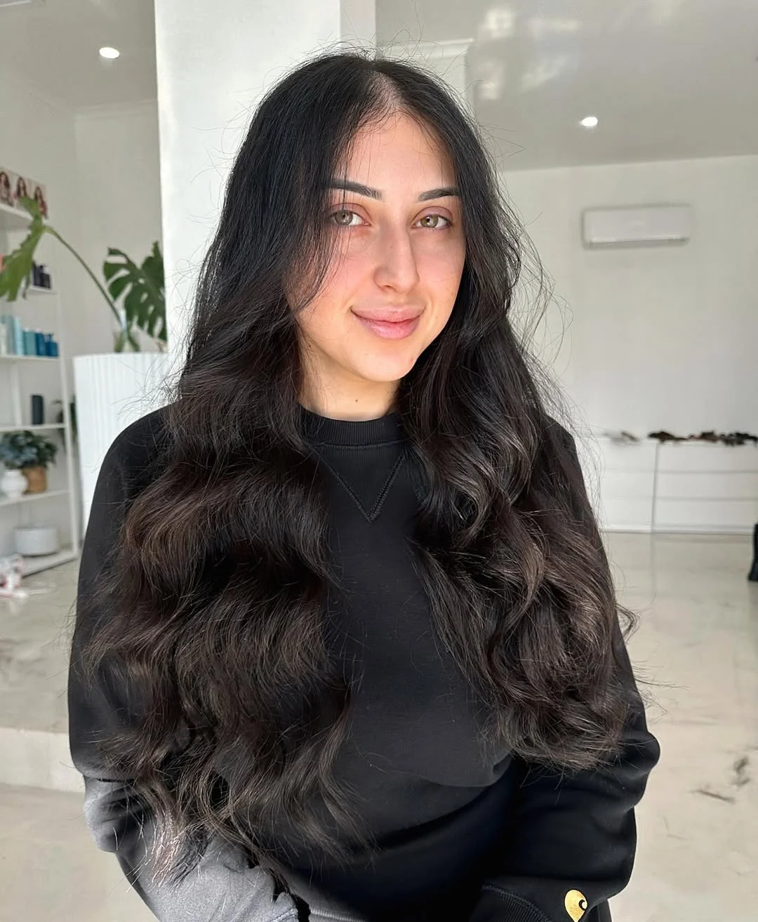 Woman with sleek, pulled-back long hair summer hairstyles 2026, accessorized with a white scrunchie and delicate gold earrings, enjoying a sunny outdoor setting.
